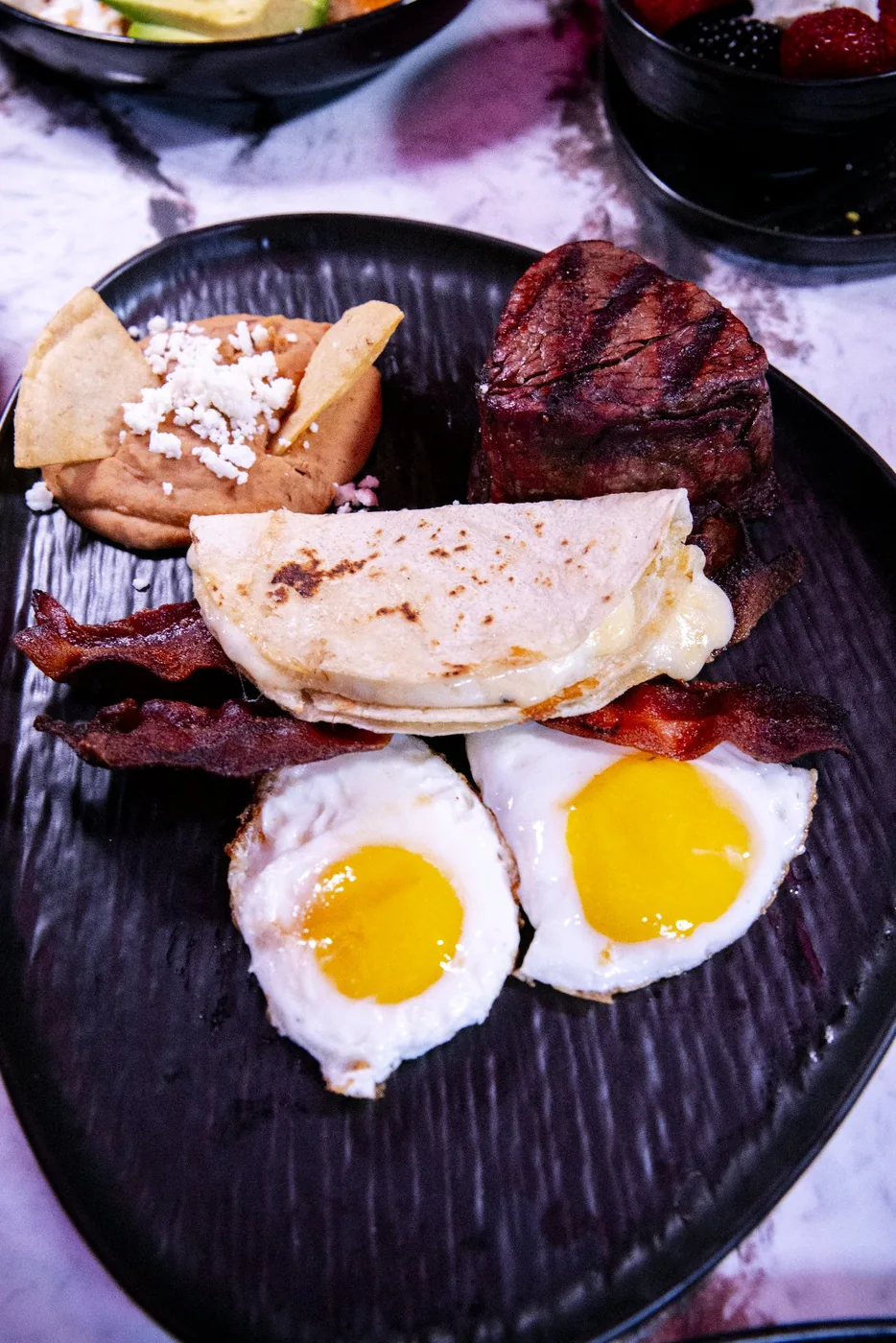 Casa Jardín breakfast on its original black plate with eggs, toast, meat, and tortillas
