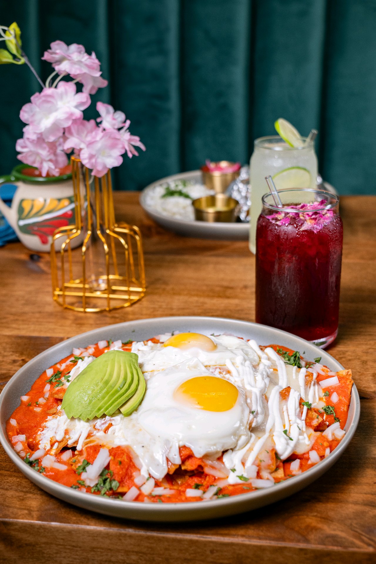 Chilaquiles with eggs and avocado at Casa Jardín, beside pink blossoms and green seating